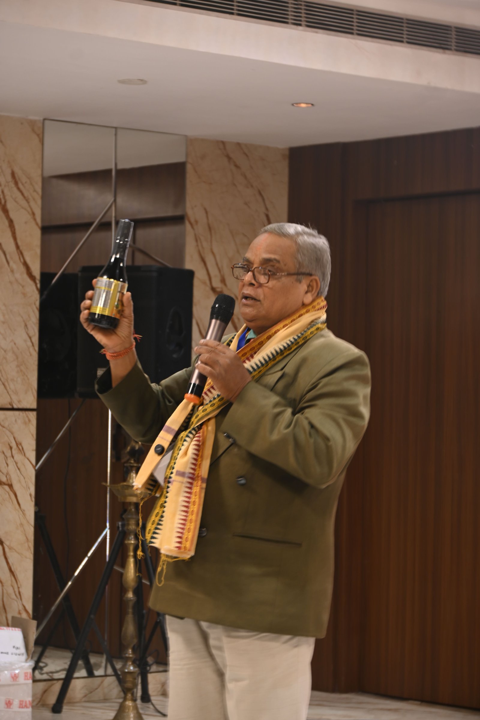 Primic Jeevamrit Juice launch event featuring a speaker presenting the Jeevamrit Juice bottle on stage